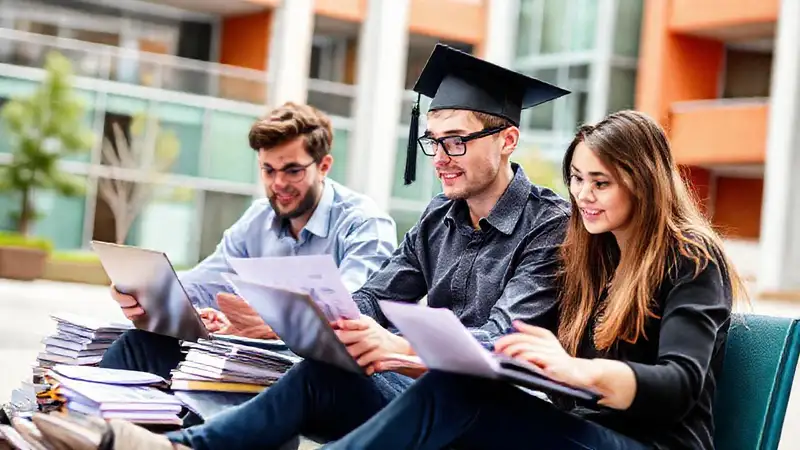 Estudiantes estudian con laptops en campus moderno