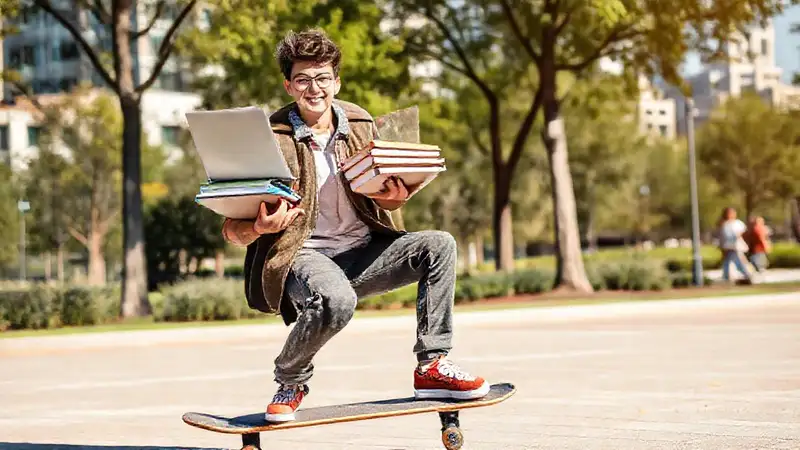 Estudiante sobre monopatín en parque soleado