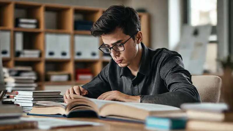 Estudiante concentrado con libros en oficina ordenada