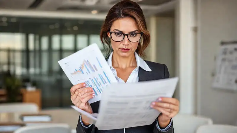 Mujer analiza documentos financieros en oficina moderna