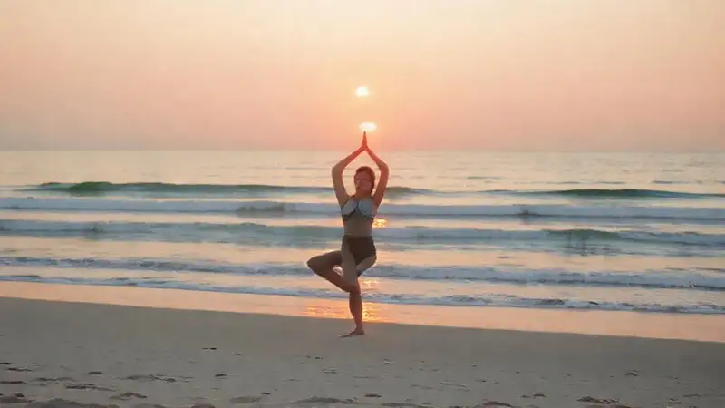 Mujer haciendo yoga en playa serena